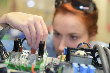 young adult female working on assembling circuit components - obrazy, fototapety, plakaty