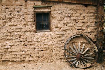 Fototapeta na wymiar Old Western Adobe Building and Wooden Wagon Wheel