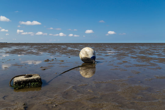 Ebbe an der Nordsee. Am Watt liegende Boje.