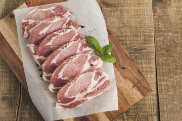 Raw pork meat with spices, wooden cutting board. Food Cooking Ingredient. Top view with copyspace.