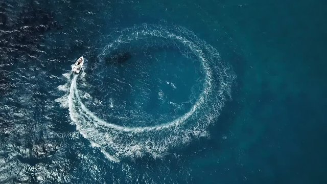 Speed motor boat creating cyrcle at sea. Aerial view from drone.