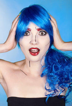 Portrait of young woman in comic  pop art make-up style.  Shoked female in blue wig on blue background