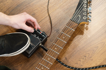 Man adjusting guitar effects pedal