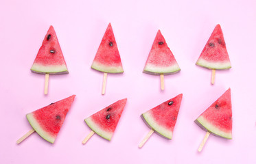 Many different bright ripe slices of watermelon on a stick on a bright pink background. Top view