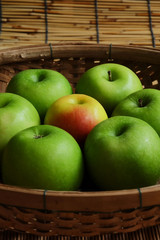 Set of green apple surround red apple in wood basket on wood mat and have some space for write wording, trendy delicious fruit for health concern people especially for weight control women or men