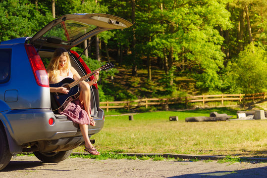 Girl with guitar on hatchback car