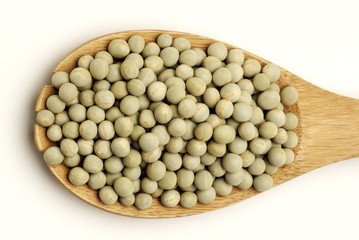 Green peas in wooden scoop spoon isolated on white background