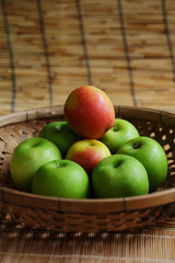 Set of green apple surround red apple in wood basket on wood mat and have some space for write wording, trendy delicious fruit for health concern people especially for weight control women or men