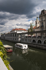 Slovenia, 24/06/2018: vista dello skyline del centro di Lubiana, la capitale slovena, con una barca turistica in navigazione naviga sul fiume Ljubljanica