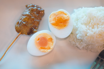 Grilled pork and boiled egg served with cooked Jasmine rice