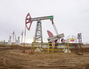 The beam pumping unit is homework, sunset in oil field. Oil pump oil rig energy industrial machine for petroleum. The pumping unit as the pump installed on a well. Equipment of oil fields.