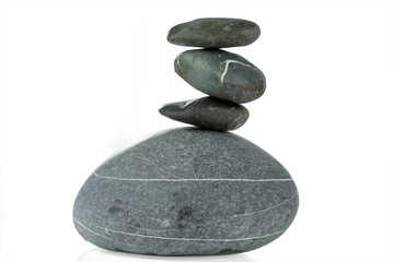 A pyramid of four stones in balance is isolated on a white background. Selective focus.