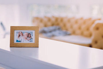 Family portrait. Beautiful family portrait in a wooden frame standing on the table and showing three cheerful relatives