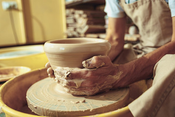Fototapeta na wymiar Creating a jar or vase of white clay close-up. Master crock. Man hands making clay jug macro.