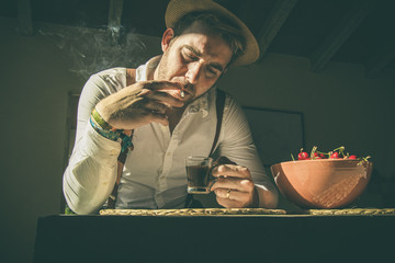 Guy drinking coffee and smoking a cigarette.