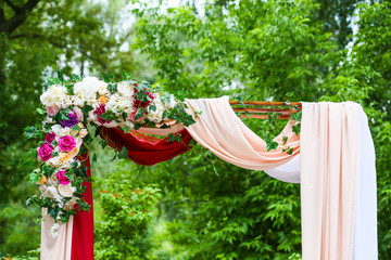 the upper part of the wedding arch is decorated with fresh flowers