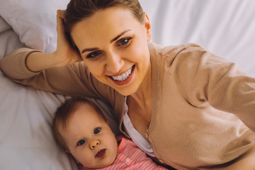 Taking photos. Cheerful emotional young mother feeling excited while taking a cute photo with her...