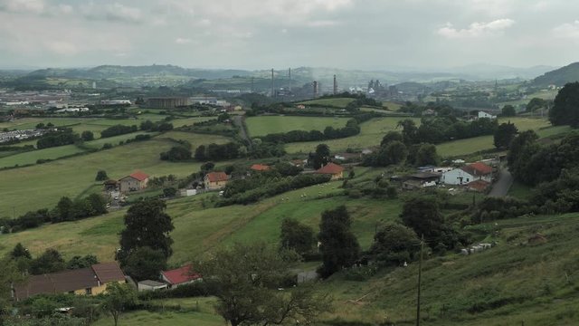 4 k timelaps frame posterise fasted video with view of green hills countryside with factory on it's background, green trees and grass, ships, smoking pipes and tranforming clouds