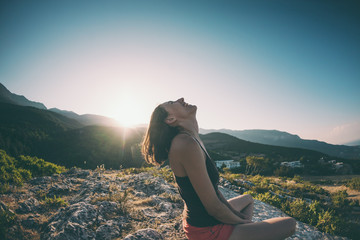 A girl is sitting on top of a mountain and smiling.