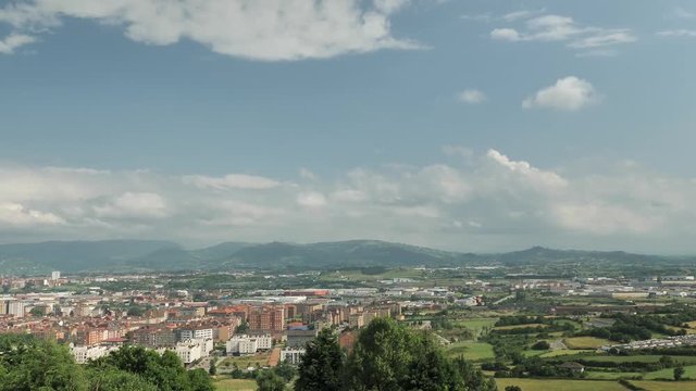 4 k Time-Laps frame posterise fasted video with view of small cosy Spanish town with speedy moving clouds, panoramic green hills, city buildings