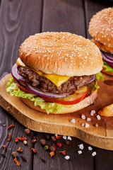 Tasty fresh meat burgers with salad and cheese served on wooden board.
