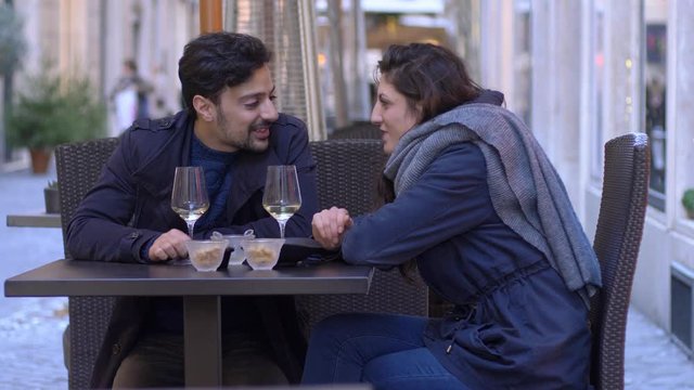 angry woman giving slap to her boyfriend during aperitif, and going away