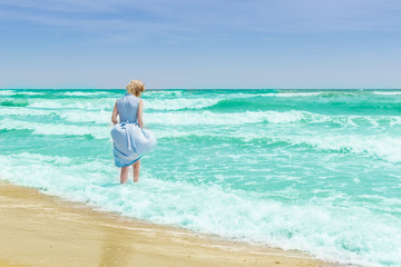 Fototapeta na wymiar Woman in blue dress in the water in the ocean, the sea.