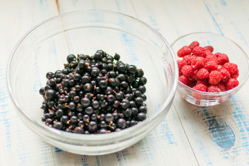Berries of raspberries and black currants. Fresh summer berries in plates.