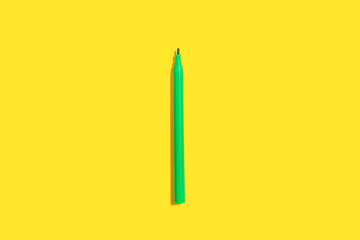 new green bright plastic felt pen lying on a yellow background without a cap. concept of office supplies