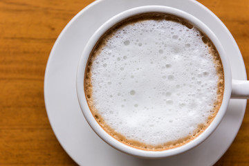 Cappuccino cup on wooden table close-up