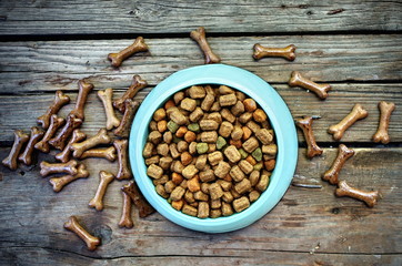 Dry dog food with bones in bowl on vintage wooden background top view.Pet food and cat food. Feeding Times and Frequency for Your Dog.