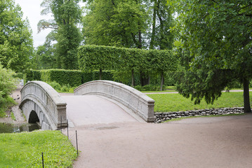 Stone bridge with an arch across the stream in the summer Park.