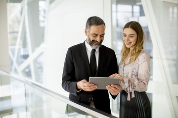 Young businesswoman and businessman look on digital tablet and discuss aout project