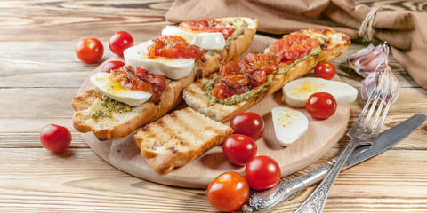 Bruschetta with baked tomatoes and mozzarella cheese. Mediterranean Kitchen. Tasty breakfast. Food banner