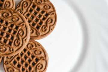 Chocolate cookies with cream filling on a white plate.