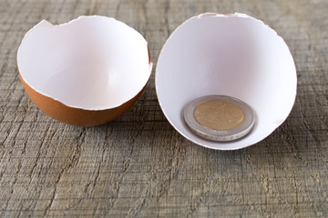 Coin 2 Euro in an egg shell. On an old wooden table. The concept of saving
