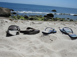 A man and a woman's pair of flip flops in the sand on the beach 