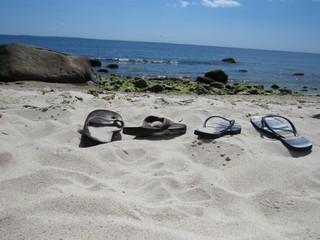 A man and a woman's pair of flip flops in the sand on the beach 