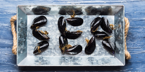 Word Sea written with raw mussels on a silver tray