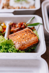 Clean food meal box: Grilled salmon fillet with tomato and bean sprout salad including carrot and corn.