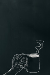 Chalk hand drawing a hand holding coffee cup with steam on black board near below of the frame.