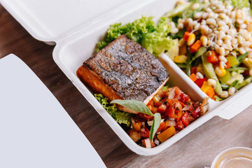 Clean food meal box: Grilled salmon fillet with tomato and bean sprout salad including carrot and corn.