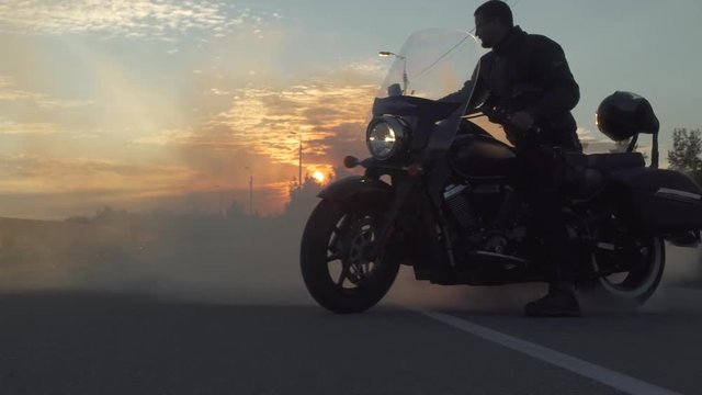Biker create a lot of smoke with a motorcycle on the road, sunset at background