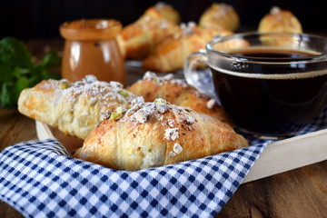 Fresh croissants sprinkled with nuts and a cup of black coffee