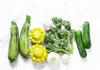 Broccoli, zucchini, squash, garlic, cucumbers - fresh organic vegetables on a light background, top view. Flat lay, copy space