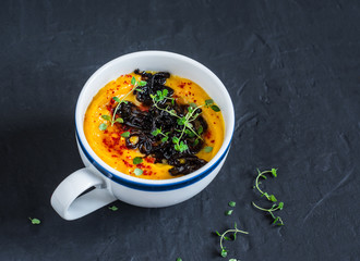 Caramelized balsamic onion pumpkin puree soup on dark background, top view. Copy space