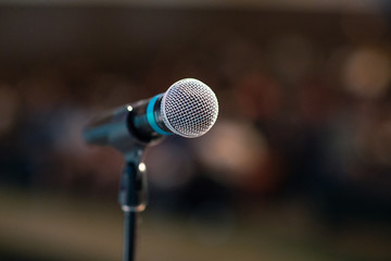 Shiny microphone on a stage in front of the full concert hall of spectaculars.