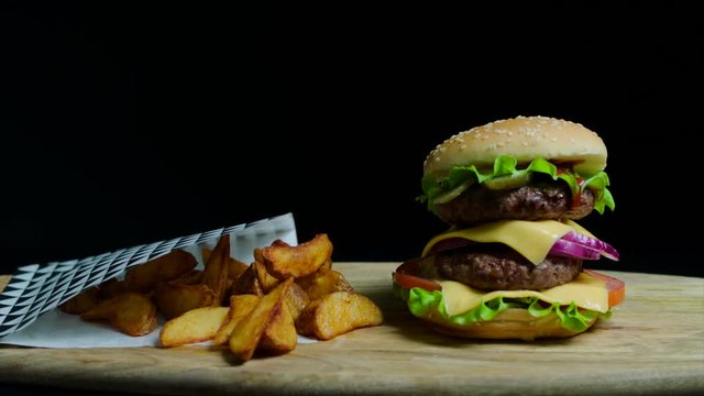 Close up of delicious burger with double cheese and french fries. Black background