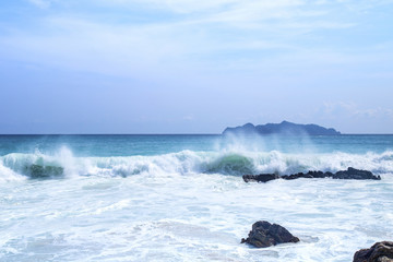 Splashing waves on the rocks and blue sky