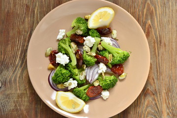 Salad with broccoli, dried tomatoes, feta, onions and pumpkin seeds
